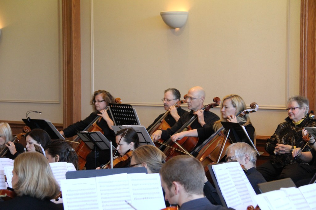 Cellists and violinists reading from their parts during the rehearsal before the 2014 Holiday Concert