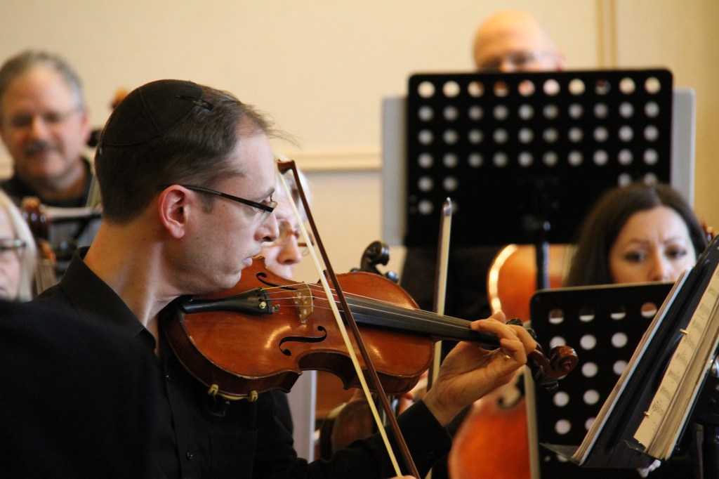 Close-up of a violinist playing at the 2014 Holiday Concert, with fellow string players around him