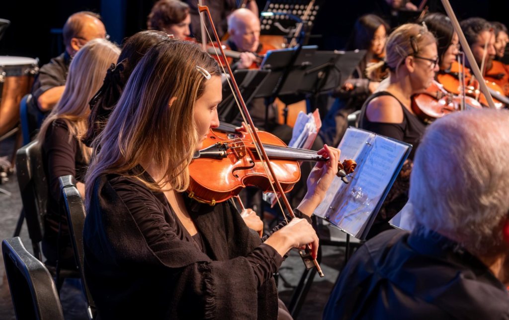 Violinists playing in concert, one in the foreground reading from her part