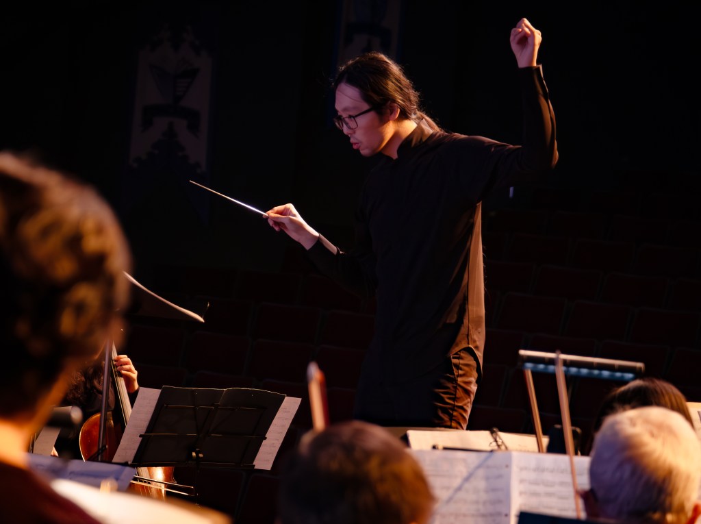 The conductor with a raised hand, leading the orchestra