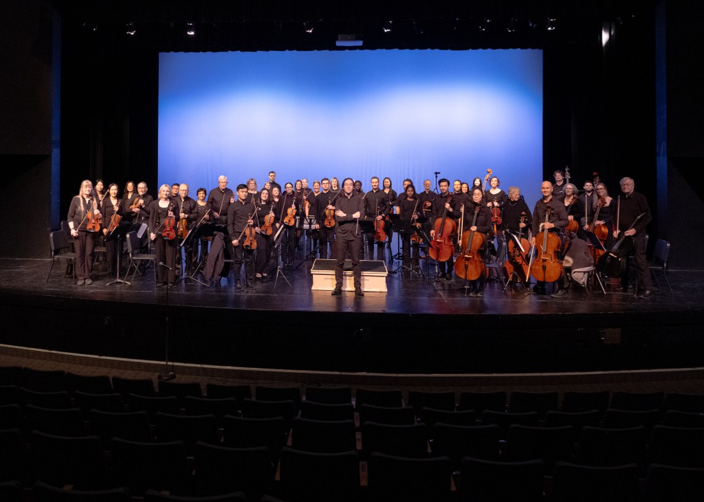 The orchestra standing to take a bow at the end of the concert