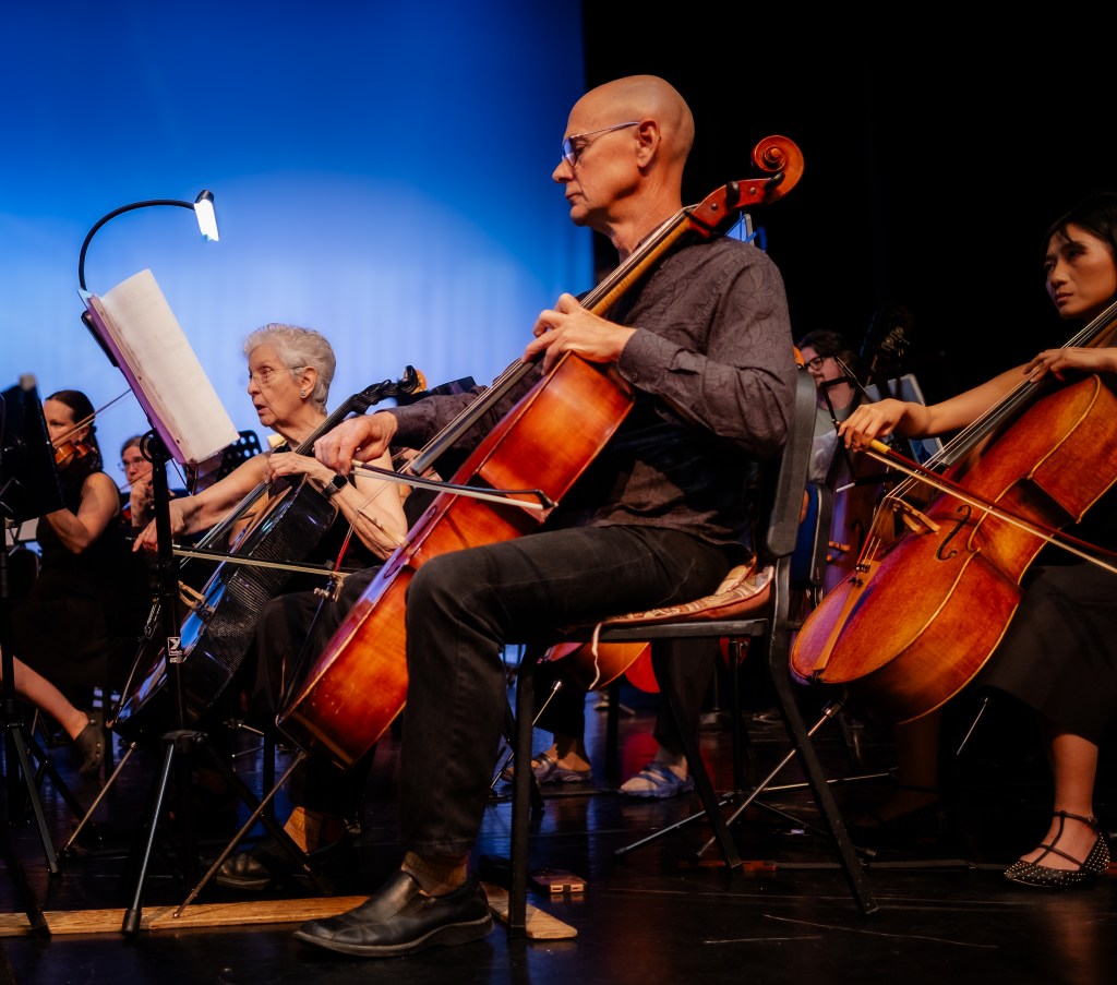 Cellists playing against the blue backdrop