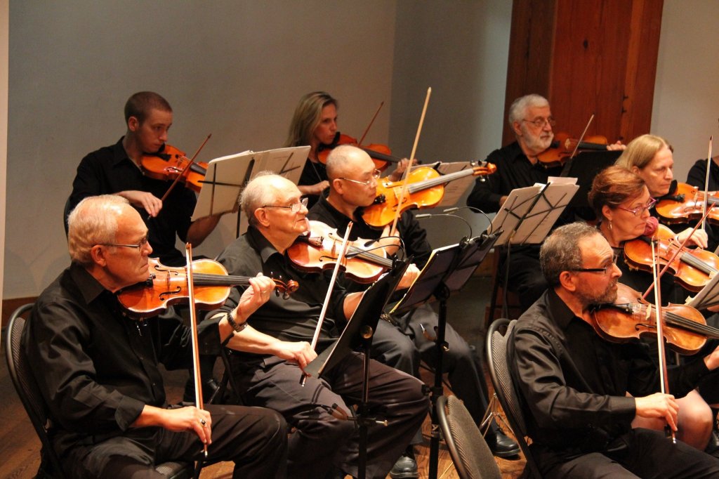 Violinists of Strings Attached Orchestra performing on stage at the George Ignatieff Theatre