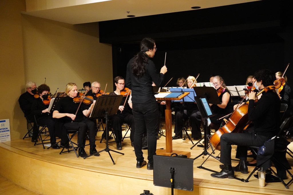 The conductor leading the orchestra in a rehearsal hall