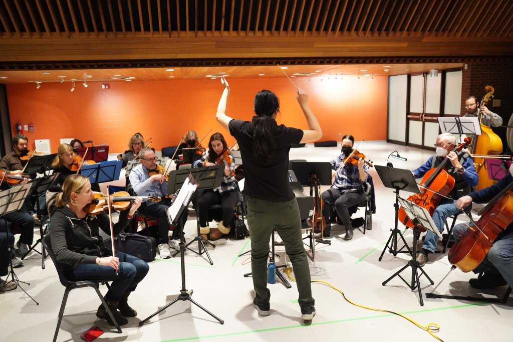 The conductor gesturing to the orchestra during rehearsal