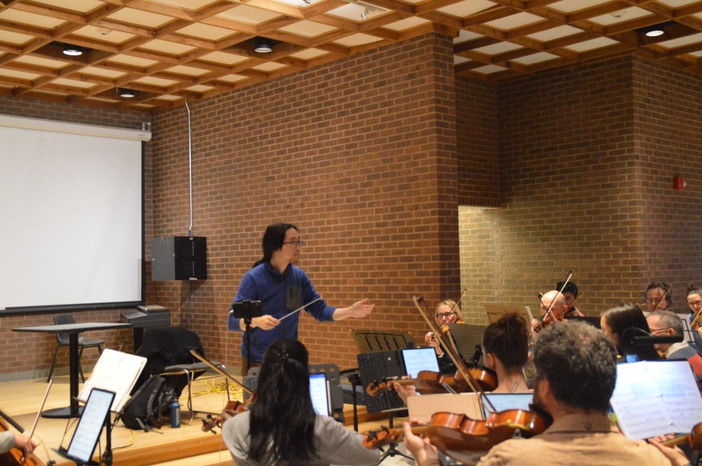 The conductor speaking to the orchestra at rehearsal