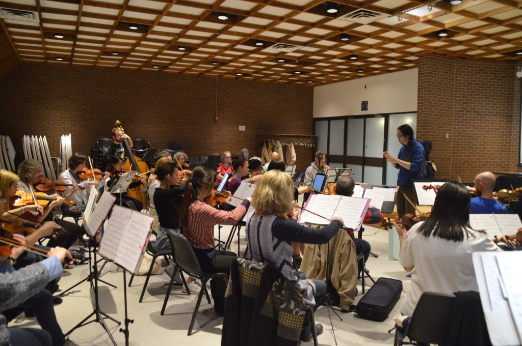 The full orchestra rehearsing under the wooden coffered ceiling