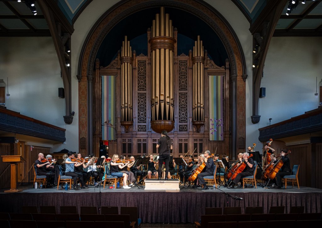 The full orchestra performing in front of the pipe organ at Trinity-St. Paul’s Centre