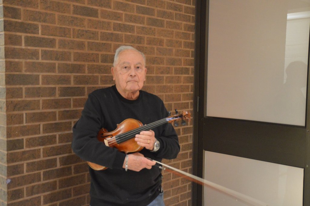 A violinist from the orchestra holding his violin and bow