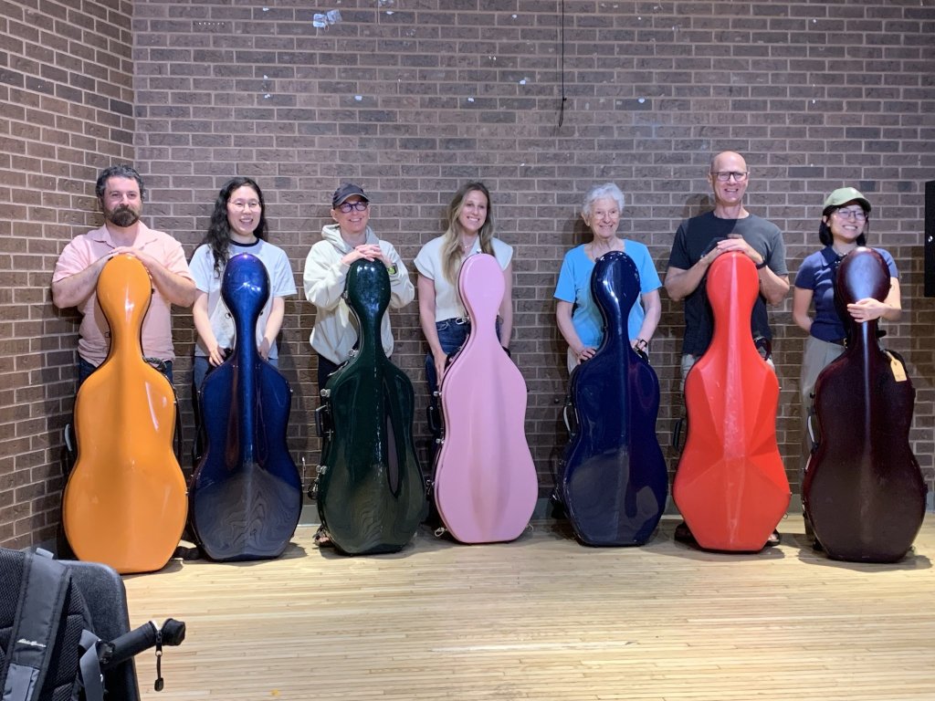 The cello section standing with their colourful cello cases