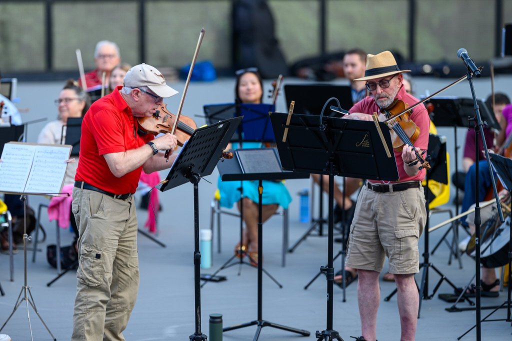 The conductor leading the players outdoors