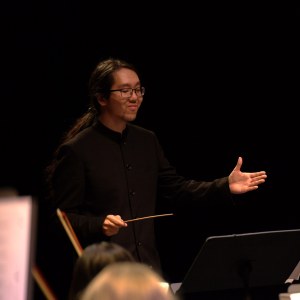 Jonathan Wong, Music Director and Conductor of Strings Attached Orchestra, conducting with baton in hand